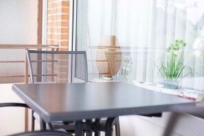 A modern room with a dark table, a mesh chair, a woven vase, and a potted plant. - (DKK1c) Holiday apartment Mole-1 - Holiday apartment "Mole 1" up to 4 persons (Timmendorfer Strand)