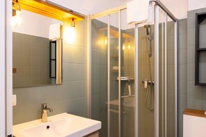 A modern bathroom with a glass-enclosed shower, a white sink, and a mirror with light fixtures. - (DKK1c) Holiday apartment Mole-1 - Holiday apartment "Mole 1" up to 4 persons (Timmendorfer Strand)