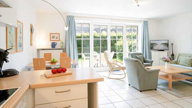 A modern living room with a dining area, a rocking chair, and a television. - (OST1) Holiday apartment "Lörper 1" - Holiday apartment "Lörper 1" up to 3 persons (Timmendorfer Strand)