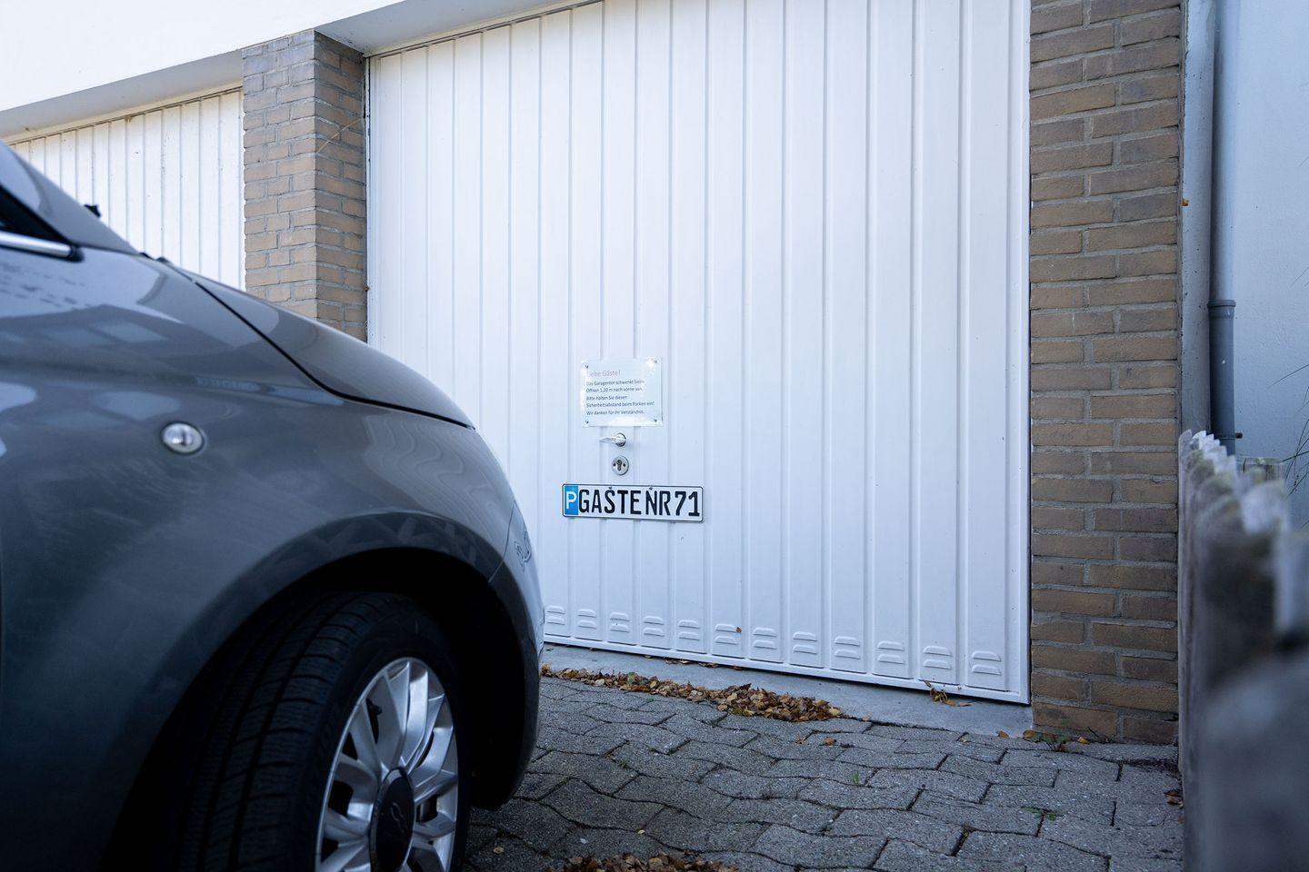 Ein Auto vor einer weißen Garagentür mit einem Parkschild.