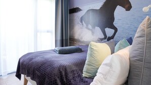 A bedroom with a bed, pillows, a window with curtains, and a wall mural of a horse.