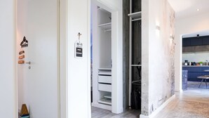 A modern interior with a white door, a visible Wi-Fi password sign, a built-in closet, and a kitchen area with a blue countertop.