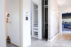 A modern interior with a white door, a visible Wi-Fi password sign, a built-in closet, and a kitchen area with a blue countertop. - (ERL41) Holiday home PIER41 - Holiday home "Pier 41" up to 6 persons (non-smoking) (Timmendorfer Strand)