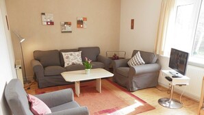 Uma sala de estar com sofá, duas poltronas, mesa de centro e rack para TV.