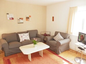 A living room with two grey sofas, a white coffee table, and a TV on a stand. - (EIC4) Holiday home Bullwinkel - Holiday home "Bullwinkel" for 3 persons ( (Timmendorfer Strand)