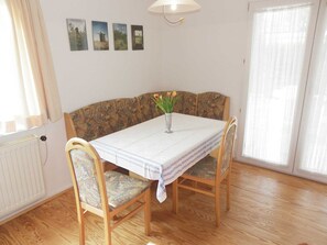 A dining area with a wooden table, patterned bench, and a vase with flowers. - (EIC4) Holiday home Bullwinkel - Holiday home "Bullwinkel" for 3 persons ( (Timmendorfer Strand)