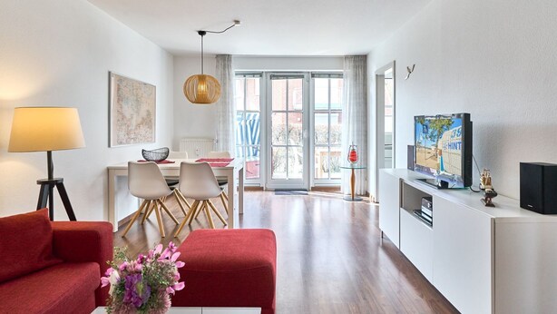 A modern living room with a dining area, a TV, and a fireplace. - (OST35c) Holiday apartment "Sonnendeck" - Holiday apartment "Sonnendeck" for 2 persons (Timmendorfer Strand)