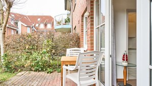 A patio with a table and chairs, a glass balustrade, and a view of neighboring houses. - (OST35c) Holiday apartment "Sonnendeck" - Holiday apartment "Sonnendeck" for 2 persons (Timmendorfer Strand)