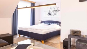A modern bedroom with a bed, a desk, and a wall-mounted light fixture. - (OST29) Apartment "Komoran" - Apartment "Komoran" for 2 persons (Timmendorfer Strand)