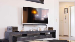 A modern living room with a large flat-screen TV mounted on a dark entertainment unit. - (OST29) Apartment "Komoran" - Apartment "Komoran" for 2 persons (Timmendorfer Strand)