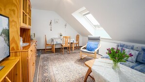 A cozy attic room with a sloped ceiling, wooden furniture, a dining table, and a skylight.