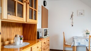 A wooden kitchen with a microwave, a wooden cabinet, and a dining area with a table and chairs.