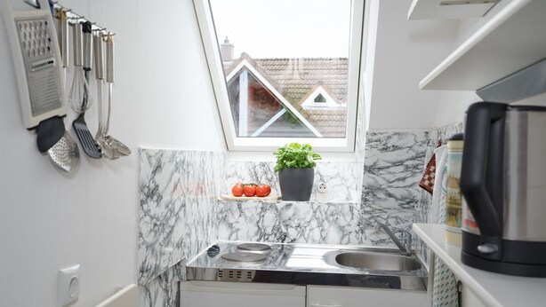 A compact kitchen with a window, a sink, a stove, and a countertop.