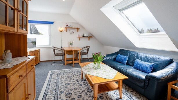 A cozy loft apartment with a dining area, a sofa, a wooden cabinet, and a skylight. - (HER14b) Holiday apartment "Hartig 2" - Holiday apartment "Hartig 2" up to 2 persons (Timmendorfer Strand)