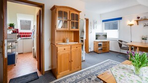 A compact kitchen with a wooden cabinet, a small dining table, and a TV. - (HER14b) Holiday apartment "Hartig 2" - Holiday apartment "Hartig 2" up to 2 persons (Timmendorfer Strand)