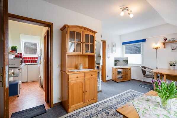 A compact kitchen with a wooden cabinet, a small dining table, and a TV.