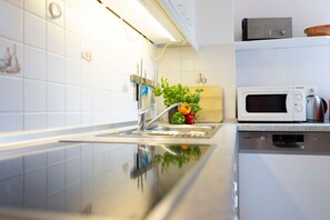 A modern kitchen with a stainless steel sink, a Bosch dishwasher, and a microwave on the countertop. - (OST9) "Kruse" Vacation Apartment - "Kruse" Vacation Apartment for up to 4 people (Timmendorfer Strand)