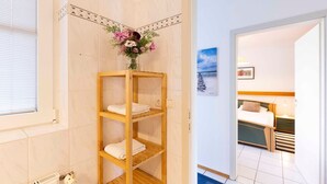 A hotel room with a wooden shelf holding towels and a vase of flowers. - (OST8) Holiday apartment "Lörper 2" - Holiday apartment "Lörper 2" up to 4 persons (Timmendorfer Strand)