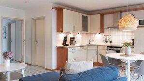 A modern kitchen with white cabinets, a coffee machine, and a hanging light fixture. - (OST8) Holiday apartment "Lörper 2" - Holiday apartment "Lörper 2" up to 4 persons (Timmendorfer Strand)