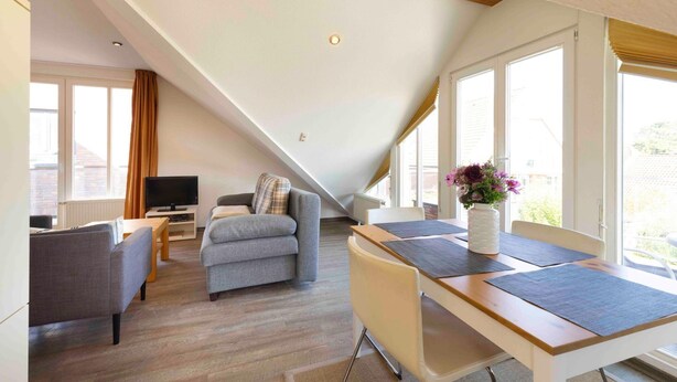 Ein modernes Schlafzimmer im Loft-Stil mit schrägen Wänden, großen Fenstern, einer Essecke und einem Fernseher.