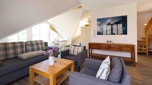 Eine moderne Loftlounge mit hohen Decken, einem Essbereich und einer Treppe.