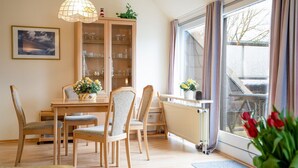 A dining area with wooden chairs, a table, and a cabinet with glass doors. - (AMW1) Apartment Garbers/Thiele - Apartment "Garbers/Thiele" to 3 (Timmendorfer Strand)