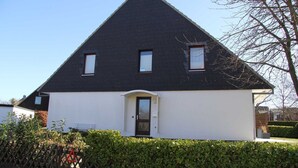 A two-story house with a dark roof and white walls, a front door, and two windows on the upper floor. - (AMW1) Apartment Garbers/Thiele - Apartment "Garbers/Thiele" to 3 (Timmendorfer Strand)