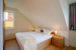 Ein Schlafzimmer mit einem Einzelbett, zwei Nachttischen, einem Fenster und einem Vorhang.