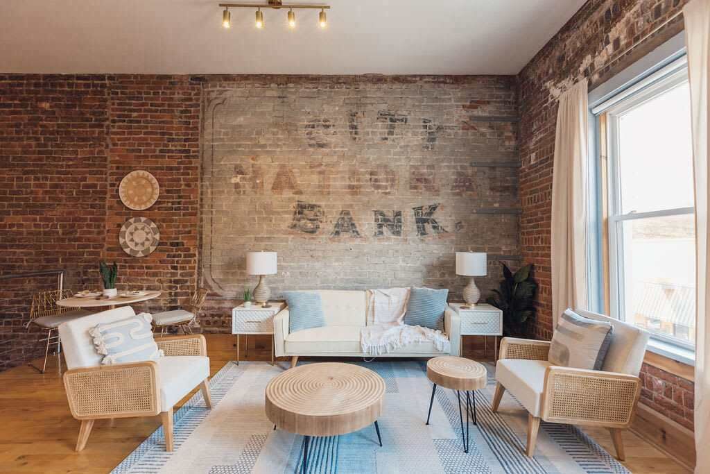 A cozy living room with a brick wall, a sofa, two side tables, and a coffee table.