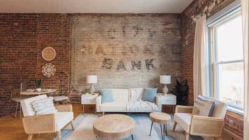 A cozy living room with a brick wall, a sofa, two side tables, and a coffee table.