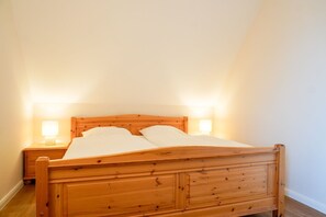 A single bed with wooden headboard and footboard, two bedside lamps, and a nightstand. - (STR74a) "Seaside Club" Vacation Rental - Seaside Club Vacation Rental for up to 4 (Timmendorfer Strand)