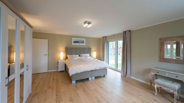 A bedroom with a bed, bedside tables, a desk, and a large window. - (STR92) Holiday apartment "Gartenresidenz Strandstraße" - Holiday apartment (Timmendorfer Strand)
