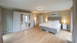 A bedroom with a large bed, a wardrobe, and a bedside table with a lamp.