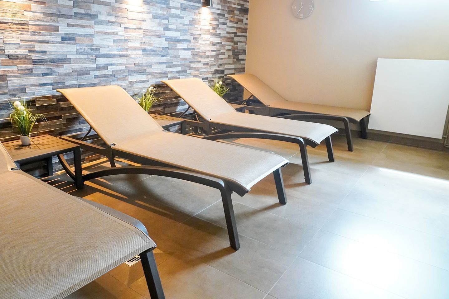 Ein Zimmer mit drei Lounge-Sesseln, einem kleinen Tisch und einer Wand mit Mosaikmuster.