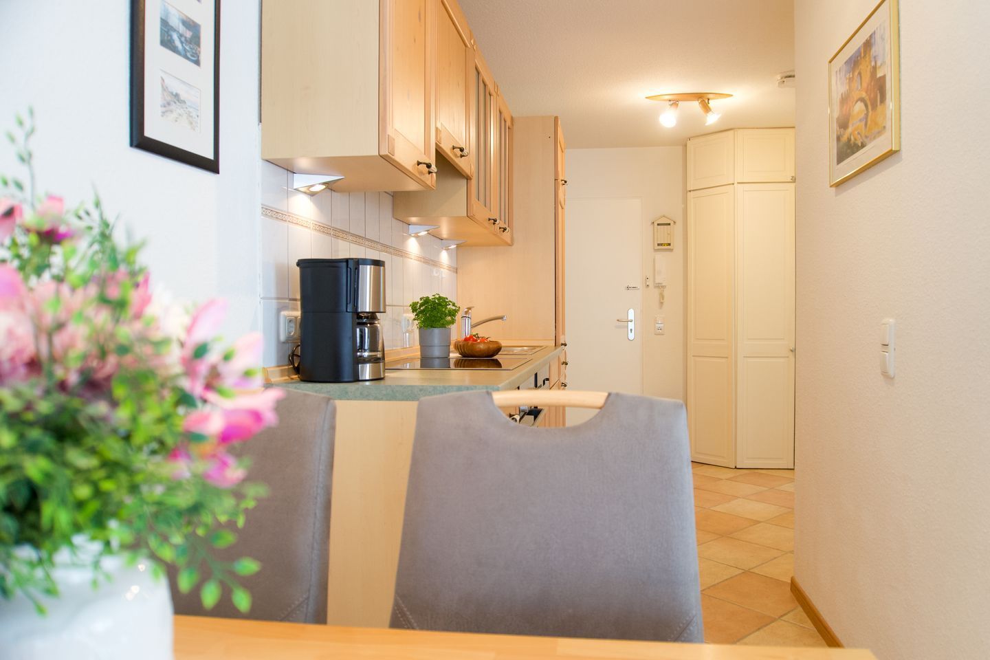 A modern kitchen with wooden cabinets, a coffee machine, and a dining area with a table and chairs.