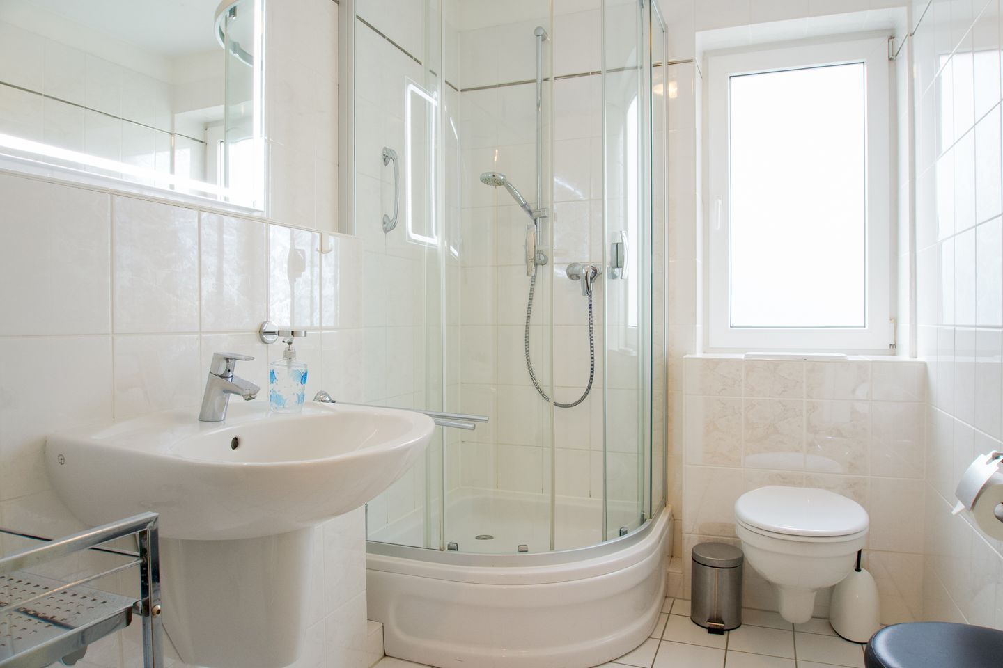 Ein modernes Badezimmer mit einer Glasdusche, einem Standwaschbecken und einer Toilette.
