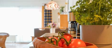 A kitchen with a copper bowl containing tomatoes and a potted plant.