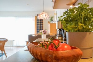 A kitchen with a copper bowl containing tomatoes and a potted plant.