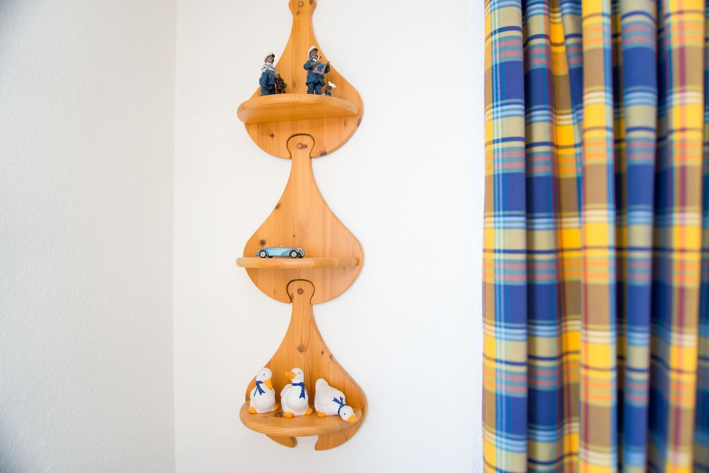 Een houten wandplank met beeldjes en een speelgoedauto.