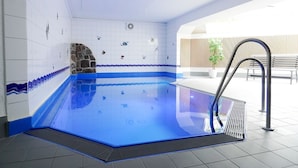An indoor swimming pool with a stone wall, tiled walls, and a metal ladder. - (TRA7) Holiday apartment "Reichelt" - Holiday apartment "Reichelt" up to 4 persons (Timmendorfer Strand)
