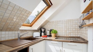 A modern kitchen with a skylight, white cabinets, and a wooden countertop. - (TRA7) Holiday apartment "Reichelt" - Holiday apartment "Reichelt" up to 4 persons (Timmendorfer Strand)