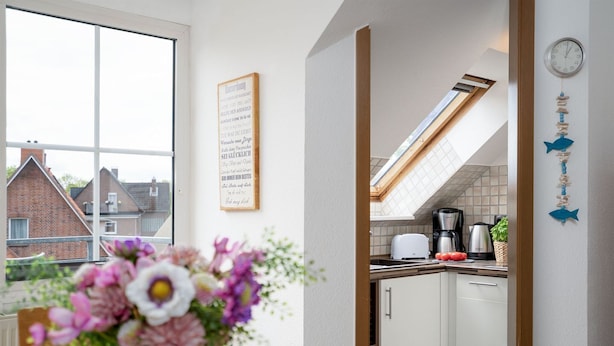 A modern kitchen with white cabinets, a skylight, and a view of neighboring houses. - (TRA7) Holiday apartment "Reichelt" - Holiday apartment "Reichelt" up to 4 persons (Timmendorfer Strand)