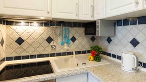 A kitchen with white cabinets, a microwave, a sink, and a kettle. - (TRA4) Holiday apartment "Hubertus "F*** - Holiday apartment "Hubertus" up to 3 persons (Timmendorfer Strand)