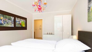 Una camera d'hotel con un letto, un armadio, un lampadario e un quadro appeso al muro.
