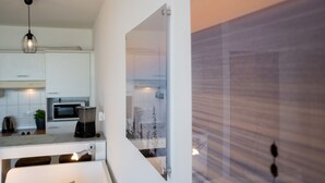 Une cuisine moderne avec des meubles blancs, un four à micro-ondes et un luminaire suspendu.
