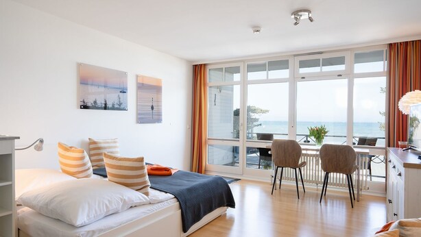 Une chambre d’hôtel moderne avec un lit, un bureau et une vue sur la mer.