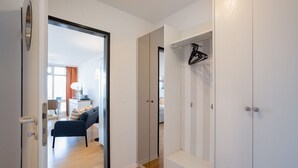 Une chambre d’hôtel moderne avec un plancher en bois, un canapé, un bureau avec une lampe et une armoire avec une tringle à vêtements.