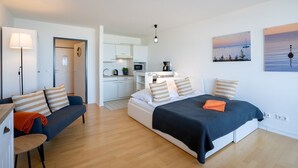 Une chambre d’hôtel moderne équipée d’un lit, d’un canapé, d’un bureau, d’une lampe et d’une kitchenette.