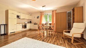 Una cocina moderna con armarios de madera, un comedor con mesa y sillas, y una alfombra blanca grande en el suelo.