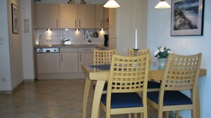 Una cocina moderna con armarios de madera, una mesa de comedor con sillas e iluminación colgante.